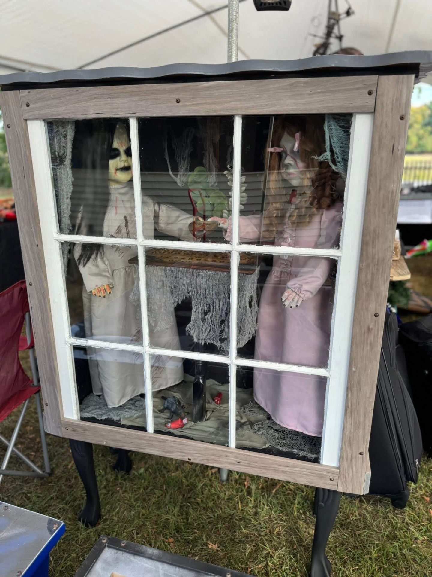 Haunted dolls with Ouija board in window cabinet